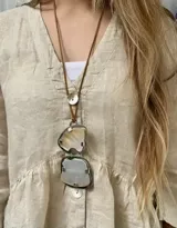 Collar largo con tiento de cuero sintético marrón y doble dije de nácar engarzado en alpaca, con detalle de botón de nácar en la parte superior.