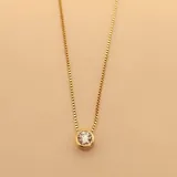 Collar de cadena fina tipo veneciana con dije de punto de luz circular, elaborado en plata 925 con baño de oro y engastado con una circonia central.
