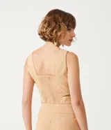 Blusa corta color beige con escote en pico y tirantes anchos. Presenta un recorte en la cintura.