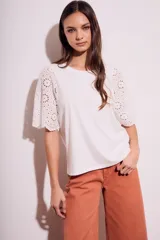Remera de algodón peinado color negro, con mangas cortas de broderie con diseño calado y terminación festoneada. Presenta un corte oversize y cuello redondo.