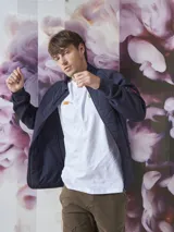 Campera azul marino con cierre frontal, cuello alto y bolsillos laterales con cierre. Tiene un parche rojo con cierre en la manga izquierda y un diseño acolchado en la parte delantera.