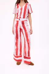 Pantalón de corte palazzo con estampado de rayas verticales rojas y texto ilegible sobre fondo blanco.