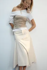 Top de escote asimétrico y manga corta, color blanco con fajín superpuesto a contraste en tono beige y detalles de frunces laterales.