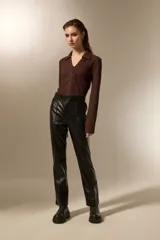 Pantalón de eco-cuero negro con corte recto y tiro alto, con costuras verticales frontales que estilizan la silueta.