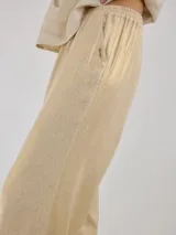 Pantalon de corte recto y tiro medio, confeccionado en lino, con cintura elastizada y tajos laterales en el ruedo.