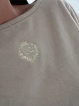Top corto azul marino de punto, con mangas cortas amplias, cuello redondo y detalle de escudo bordado en la parte delantera.