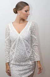 Vestido blanco de tul bordado con hilo de seda y cintas, con escote en V y mangas largas.