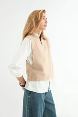 Chaleco tejido de punto color verde salvia, con cuello redondo y diseño sin mangas. Presenta detalles de pequeños apliques brillantes distribuidos por toda la prenda.