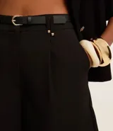 Short color visón de corte sastrero, tiro alto, con pliegues delanteros, trabillas y cinturón fino de cuero sintético.