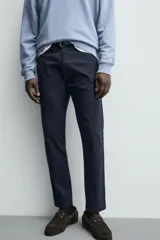 Pantalón chino de corte ajustado, color beige, con bolsillos laterales y bolsillos traseros de vivo. Cuenta con cierre frontal de cremallera y botón.