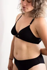 Soutien Summum confeccionado en tul y lycra de doble capa, color negro, sin aro ni relleno, con detalles de ribetes ondulados y espalda completamente regulable.