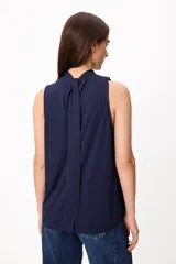 Blusa sin mangas color crema, con cuello alto fruncido y diseño holgado.
