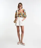 Short baggy de cintura alta color crudo, confeccionado en sarga de algodón. Cuenta con trabillas, cintura elástica, bolsillos delanteros y traseros, cierre con doble botón y cremallera, bajo plegado y pespuntes contrastantes.