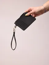 Billetera de poliuretano color celeste, con cierre de cremallera y correa de mano.