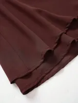 Vestido corto marrón oscuro con escote halter profundo y drapeado tipo cascada en el busto. La falda es corta con capas superpuestas y volados.