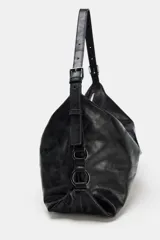 Bolso tipo saca color negro, de diseño flexible y acabado con efecto gastado. Cuenta con un asa ajustable para el hombro, detalles de hebillas y herrajes metálicos laterales, además de un cierre superior de cremallera metálica.
