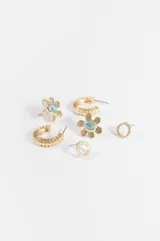 Set de tres pares de aros plateados de diferentes diseños: argollas pequeñas con textura acanalada, aros pequeños con diseño de flor con piedra celeste en el centro y aros pequeños con dije circular.
