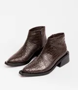 Bota corta de cuero vacuno con acabado metalizado y textura de reptil. Presenta punta fina, cierre lateral interno y taco cuadrado de madera.