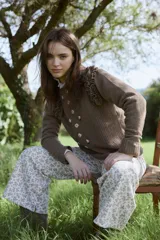 Sweater de lana color marrón con volados en los hombros, bordados florales artesanales en el frente y detalles de tejido calado.