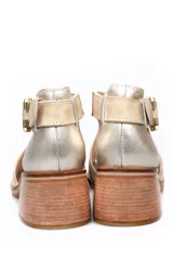 Sandalia de cuero negro con taco bloque efecto madera, puntera abierta y tira ajustable al tobillo con hebilla metálica dorada.