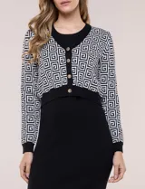 Conjunto de vestido midi y chaqueta de punto. Vestido negro acanalado al cuerpo, sin mangas y con escote redondo. Chaqueta corta con mangas largas y estampado geométrico blanco y negro, con cierre frontal de botones dorados.