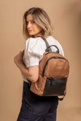 Mochila urbana de diseño combinado, con cuerpo principal en color tostado y bolsillo frontal con cierre en color negro. Presenta herrajes negros y correas ajustables.