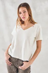 Remera básica de algodón peinado color marfil, de manga corta y cuello en V, con detalle de pequeño bordado rojo en el escote.