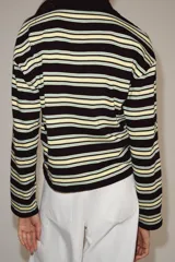 Polo de manga larga confeccionado en algodón, con diseño a rayas horizontales en tonos amarillos, verdes y oscuros. Presenta cuello solapa, cierre frontal con botones y bajo recto.
