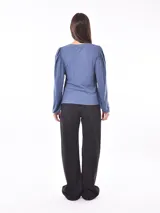 Remera color caqui de tejido acanalado, con mangas largas abullonadas en los hombros y puños ajustados.