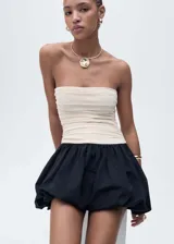 Vestido corto de diseño combinado con cuerpo strapless drapeado en color beige y falda estilo globo en color negro. Cuenta con cierre lateral invisible.