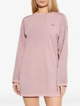 Vestido corto de algodón color rosa, de corte relajado, manga larga y cuello redondo. Presenta costuras externas visibles y el logo de la marca bordado en el pecho.