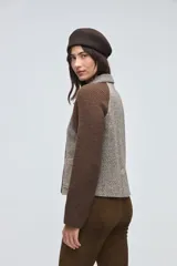 Campera corta con cuerpo de lana tejida en textura tweed y mangas de punto liso en color marrón. Presenta cuello camisero, cierre frontal con botones y bolsillos frontales tipo plaque.