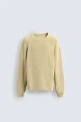 Sweater de punto canalé color beige, con cuello redondo y mangas largas con diseño raglán.