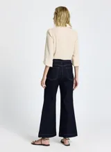 Pantalón de jean de tiro alto, color azul oscuro, con corte flare y costuras en color ocre.