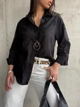 Camisa negra con bordados, de corte clásico y manga 3/4.