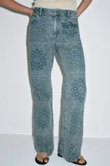 Jeans de tiro alto con corte flare y diseño de tejido jacquard con patrón floral. Presenta cinco bolsillos, trabillas en la cintura y cierre frontal con cremallera y botón.