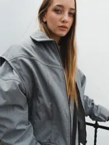 Campera gris con cierre frontal, cuello camisero y mangas largas con puños elásticos.