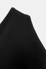 Body de tejido liso color azul claro, con escote asimétrico de un solo hombro y cierre inferior con broches a presión.