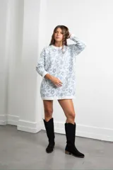 Buzo de punto con diseño estampado floral en tonos blanco y azul, de corte holgado y largo tipo vestido, con cuello redondo y mangas largas.