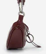 Cartera tipo riñonera de tamaño pequeño, confeccionada en poliuretano con acabado brillante. Presenta un diseño de media luna con cierre de cremallera metálica, decorado con tiradores circulares. Incluye una correa de cadena metálica para llevar al hombro o cruzada.