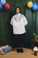 Camisa de corte oversize con mangas largas y puños abotonados. Presenta un diseño bicolor con cuerpo blanco y un canesú delantero con estampado floral multicolor.