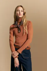 Polera de tejido fino color negro, con cuello alto y mangas largas con terminación sutilmente fruncida. Diseño ajustado al cuerpo.