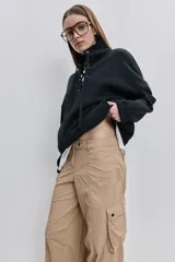 Pantalón cargo negro de corte relajado y pierna ancha con bolsillos laterales con solapa, cintura con doble broche y cierres metálicos en los tobillos.