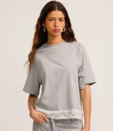 Remera femenina gris de algodón con cuello redondo, manga raglán corta y ruedo con detalle de encaje blanco.