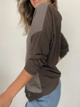 Remera blanca de manga larga con cuello redondo y detalle de tejido crochet en el dobladillo. Incluye un collar fino dorado como accesorio.