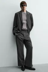 Blazer oversized fit de hombre, color gris oscuro con rayas verticales finas. Cuello con solapas de muesca, manga larga con puño abotonado, bolsillos de solapa en la cadera y bolsillo interior. Cierre frontal de un botón y abertura en el centro de la espalda.