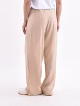 Pantalón de vestir color oliva, de corte amplio y tiro alto, con pinzas en la cintura y textura arrugada.