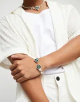 Pulsera rígida plateada con dos cristales facetados triangulares de color verde en los extremos.