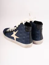 Zapatillas de caña alta color beige con detalles en marrón y animal print de leopardo en el tobillo. Presentan una estrella en el lateral y cordones blancos.