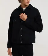 Campera de hombre de jean negro, modelo regular, con cuello inglés, abotonado frontal, dos bolsillos con solapa en el pecho y manga larga ajustada.